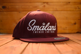 Maroon cap with 'Småland Sweden for Real' text on a wooden surface by mangobeard