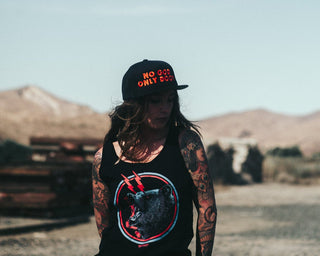 Person wearing a black t-shirt with a graphic design and denim shorts standing in a desert landscape.