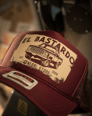 Burgundy mesh trucker cap for El Bastardo General Store, with a distressed cream graphic of a pickup truck.