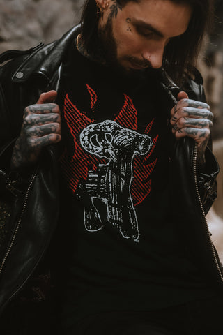 Model holding open a black leather jacket to reveal a black T-shirt with a white goat skull and red flame graphic.