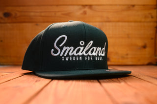 Spruce cap with 'Småland Sweden for Real' text on a wooden surface by mangobeard
